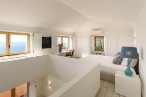 a white bedroom with a white bed and a blue lamp at Casa Pôr do Sal - Boutique Suites, Sea Views & Heated Pool in Luz