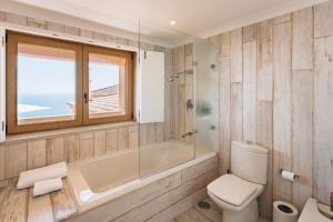 a bathroom with a tub and a toilet and a window at Casa Pôr do Sal - Boutique Suites, Sea Views & Heated Pool in Luz