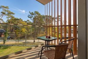 a balcony with a table and chairs and a large window at PINEA Apartamenty in Pobierowo