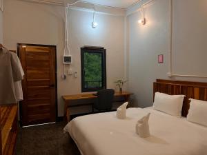 a bedroom with two beds and a desk and a window at Valley Villa Hotel in Nongkhiaw