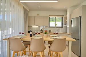 a kitchen with a wooden table with chairs and wine glasses at Arillas Villas in Arillas +38 photos