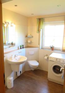 a bathroom with a sink toilet and a washing machine at Ferienwohnung Bartels in Petersdorf mit Terrasse in Fehmarn +4 photos