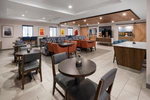a restaurant with tables and chairs and a bar at Holiday Inn Express Syracuse-Fairgrounds by IHG in Warners