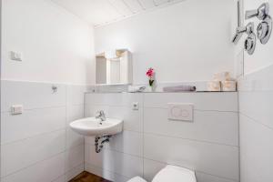 a white bathroom with a sink and a toilet at Ferienwohnung Elbufer 3a in Stadt Wehlen +18 photos