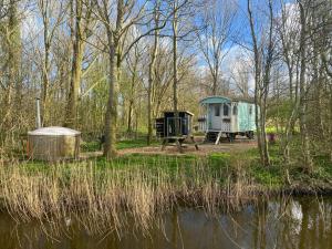 a campsite with a tent and a table next to a lake at Pipowagen Utewyn in Reitsum