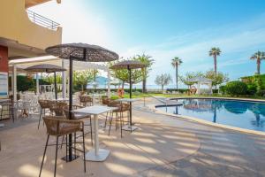 a patio with tables and chairs next to a pool at Prestige Victoria in Roses