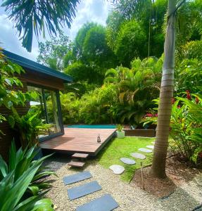 a garden with a wooden deck and a house at Moderne Lodge Tropical in Les Abymes