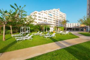 a group of lounge chairs and an umbrella in a park at Prestige Victoria in Roses