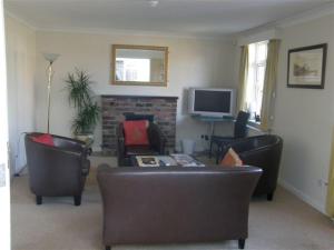 a living room with a couch and chairs and a tv at Travelrest Fareham Solent Gateway in Fareham