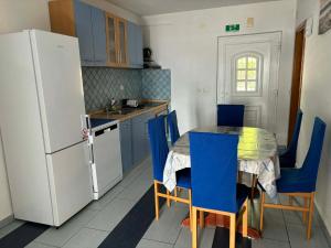 a kitchen with a table and blue chairs and a refrigerator at Apartments & Room MaDi in Senj