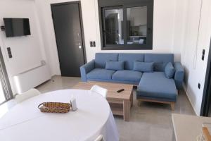 a living room with a blue couch and a table at MareMonti VILLAS in Sidhirodhromikós Stathmós Krioneríou