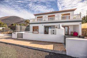 a white house with a balcony and mountains in the background at vv Cerca Nueva in Las Manchas
