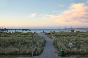 a path leading to a beach with a pier at Bretterbude Heiligenhafen in Heiligenhafen