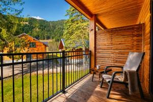 a porch with a chair and a table and a fence at Stylish Loft Apartment with Mountain View near the Lake in Afritz
