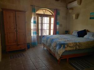 a bedroom with a bed and a large window at Ta' Karkar Villa Bed and Breakfast in Xagħra