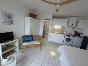 a bedroom with a bed and a chair and a kitchen at Au clair soleil in Frontignan +3 photos
