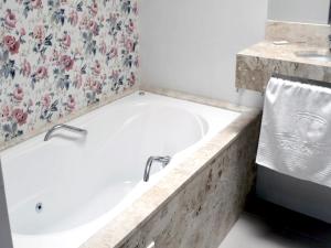 a bath tub in a bathroom with a floral wallpaper at Hotel Kalimera in Clementina