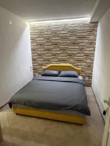 a bed in a room with a brick wall at Baywatch Apartmans in Brca