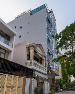 a white building with a balcony in front of it at Bluzen Hotel in Danang