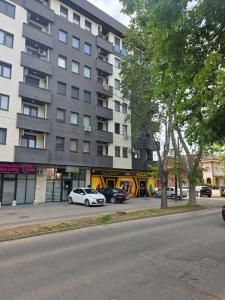 a large building with cars parked in front of it at Navigator Apartment in Bijeljina