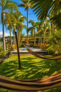 a hammock in a park with palm trees at Refúgio Casinha Branca in Duque de Caxias