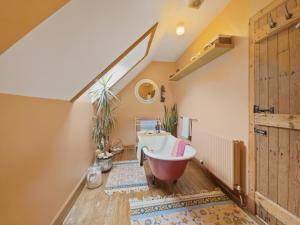an attic bathroom with a claw foot tub and a plant at The Archway Suite in Peebles +16 photos
