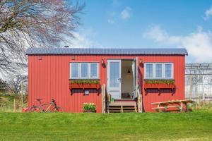 a red tiny house on a green field at Bankhead Shepherds Hut in Stirling