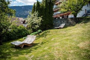 two benches sitting on a grassy hill next to a building at Rumpelehof in Villandro