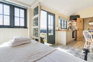a bedroom with a bed and a kitchen with windows at Bankhead Shepherds Hut in Stirling