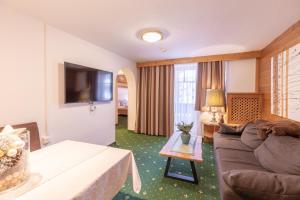 a living room with a couch and a television at Bergidyll & Hotel Trofana in Leutasch