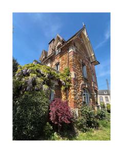 an old brick building with ivy growing on it at Le Lierre et La Rose in LʼAigle