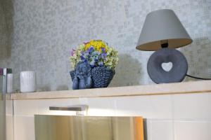a table with a lamp and a vase with flowers on it at Domus Mazzini in Tivoli