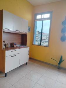 a kitchen with white cabinets and a window at Casa das Hortas in São Luís