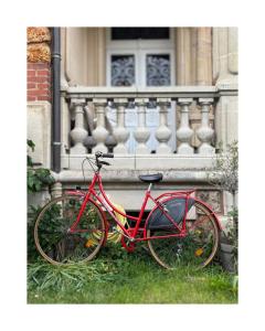 a red bike parked in the grass in front of a building at Le Lierre et La Rose in LʼAigle