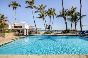 a swimming pool with palm trees and a house at Condo Cabrinha - Kite Beach Cabarete in Cabarete
