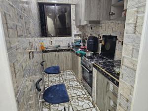 a kitchen with a sink and two blue stools at Kim'sPlace in Mombasa