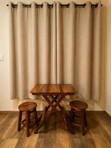 a wooden table and two stools in front of a curtain at Refúgios de Mauá - Chalé Serra in Visconde De Maua