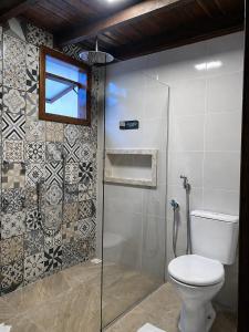 a bathroom with a toilet and a glass shower at Refúgios de Mauá - Chalé Serra in Visconde De Maua