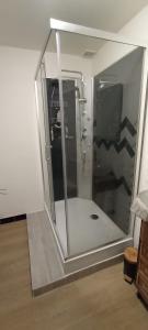 a shower with a glass door in a room at Chambres d'hôtes Las Carbounieros in Auriac