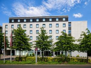 a white building with trees in front of it at Sunday Hotel Düsseldorf City Nord in Düsseldorf