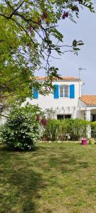 a white house with blue windows and a yard at SERINITY in Sainte-Soulle
