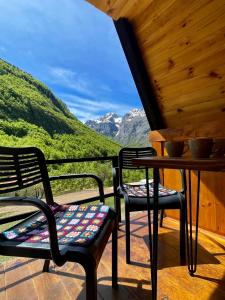 two chairs and a table on a porch with mountains at A&R cottages in Vusanje