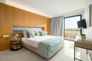 a hotel room with a bed and a tv at Agua Hotels Riverside in Ferragudo