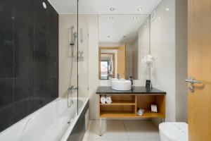 a bathroom with a tub and a sink and a toilet at Agua Hotels Riverside in Ferragudo