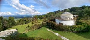 a building on a hill with a horse in a field at Cinco Elementos Glamping in Chiquinquirá