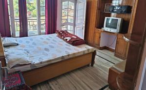 a bedroom with a bed and a tv in a room at Ghar Family-Homestay- 2 Room -Prime Location - Balcony kitchen-Don't book Single Room Book a complete Home in Solan +3 photos