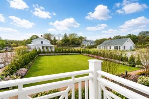 a white fence in front of a yard with a garden at Canoe Place Inn & Cottages in Hampton Bays
