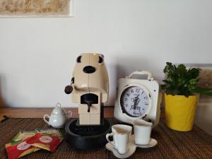 a coffee maker with cups and a clock on a table at Almarè Confort Rooms in Terrasini