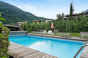 a swimming pool with lounge chairs and a table at Residence Sonngart in Lagundo