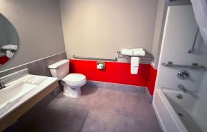 a bathroom with a white toilet and a red wall at Super 8 by Wyndham Windsor in Windsor